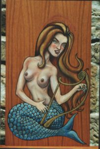 Pintura sobre madera en estilo medieval de una sirena desnuda de larga melena rubia con cola azul turquesatocando un arpa
